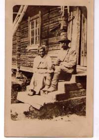 Valokuva: Vanha  emäntä  ja  isäntä  hirsitalon  portailla. Koko 9x 14 cm