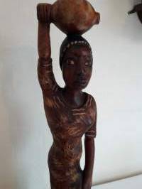 Pienoispatsas. Etelä-amerikkalainen ylväästi taakkaansa kantava neito  Tukeva puinen käsityö.Korkeus 52 cm. leveys, rinnankorkeudelta 11cm, jalusta 10 cm