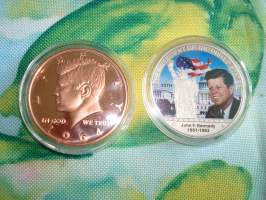 2 kpl erilaisia John F. Kennedy, JFK, mitaleita hienossa rasiassa. 1 av oz (28,35 g) .999 puhdasta kuparia sekä hopeoitu/värillinen mitali. Mitaleiden halkaisija