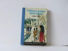 Villikissa katsoo lasin takaa