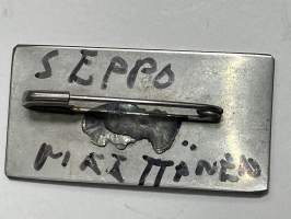 SIG-rintamerkki, Matti &quot;Inksu&quot; Inkisen (Inkinen) perustaman yhtyeen ensimmäisiä &quot;fanituotteita&quot;, metallinen rintamerkki, tekijä Seppo Määttänen (&quot;Raision Rembrandt&quot;)
