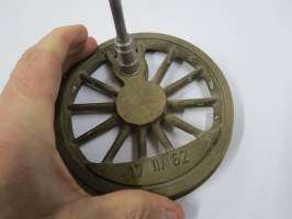 VR 100 vuotta 1962 -lipputanko, ilmeisesti VR:n jollain omalla valimolla / konepajalla valmistettu juhlatanko, jossa tyylitelty veturin "pyörä", messinkiä