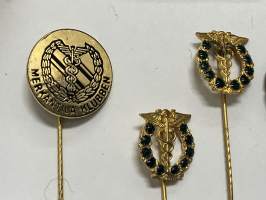 Merkantila klubben Åbo Akademi -erä sen toimintaan liittyviä yhden henkilön merkkejä; Ruusuke, kaulariipus, neulamerkit, mitali, kangasmerkit, tarra -osa hopeaa