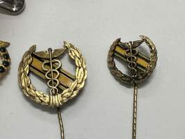 Merkantila klubben Åbo Akademi -erä sen toimintaan liittyviä yhden henkilön merkkejä; Ruusuke, kaulariipus, neulamerkit, mitali, kangasmerkit, tarra -osa hopeaa