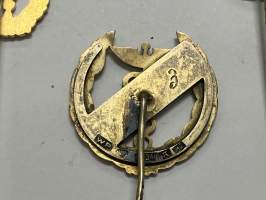 Merkantila klubben Åbo Akademi -erä sen toimintaan liittyviä yhden henkilön merkkejä; Ruusuke, kaulariipus, neulamerkit, mitali, kangasmerkit, tarra -osa hopeaa